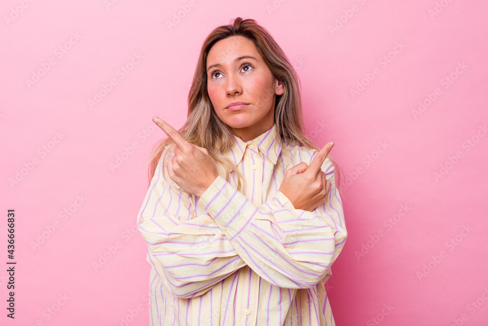 Young australian woman isolated points sideways, is trying to choose between two options. Young australian woman isolated points sideways, is trying to choose between two options.