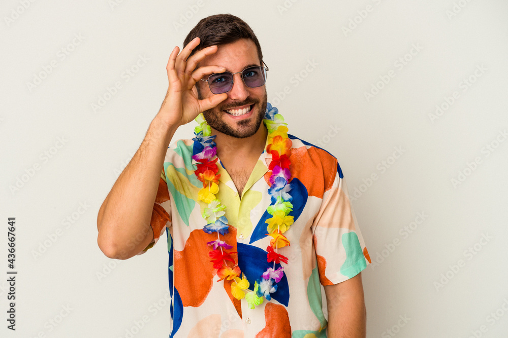 Young caucasian man dancing on a hawaiian party isolated on white background excited keeping ok gesture on eye. Young caucasian man dancing on a hawaiian party isolated on white background excited keeping ok gesture on eye.