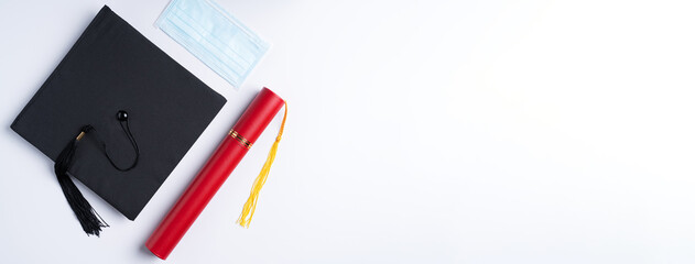 Graduation academic cap with diploma and mask isolated on white table background.