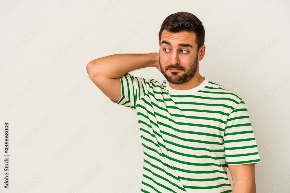Young caucasian man isolated on white background touching back of head, thinking and making a choice. Young caucasian man isolated on white background touching back of head, thinking and making a choice.