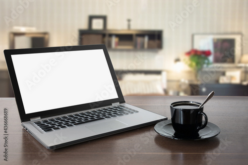 Laptop with empty blank screen on wooden table top and modern blur living room as background. Template, mock up for disoaly your home products. Work at home.