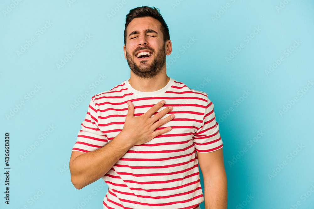 Young caucasian man isolated on blue background laughs out loudly keeping hand on chest. Young caucasian man isolated on blue background laughs out loudly keeping hand on chest.