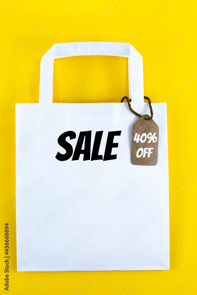 White paper shopping bag with 40% discount on yellow background. White paper shopping bag with 40% discount on yellow background.