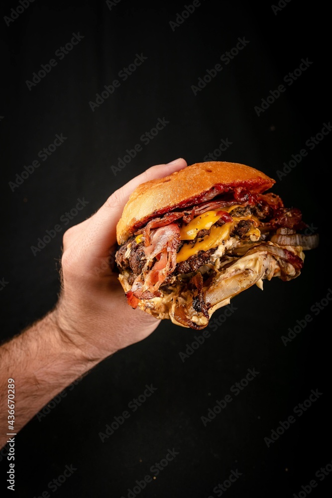 Hand grabbing a big handmade burger Hand grabbing a big handmade burger