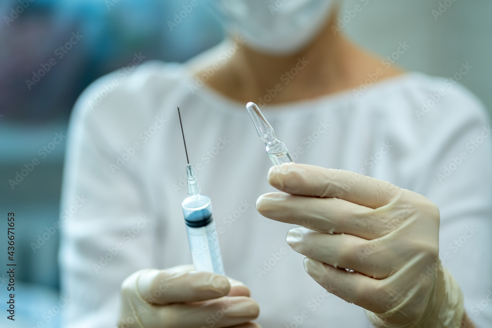 Ampoule and syringe in the doctor's hand. Ampoule and syringe in the doctor's hand.