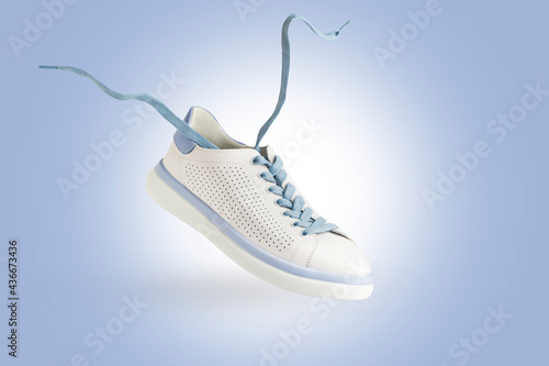 White sneakers flying. Fashionable sports shoes with laces.