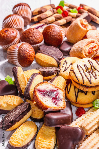 Assorted various cookies and cupcakes scattered on wooden boards background