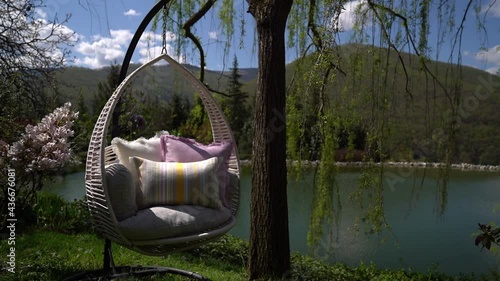 Swing chair by the lake with beautiful decorative pillows.