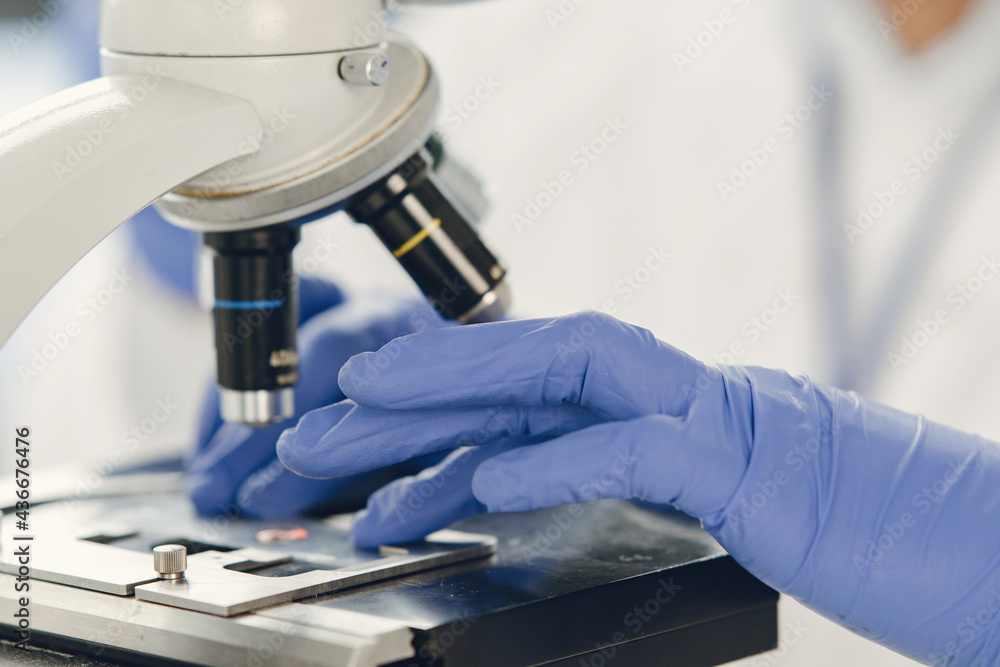 Unrecognizable lab worker inspecting blood sample under microscope Unrecognizable lab worker inspecting blood sample under microscope