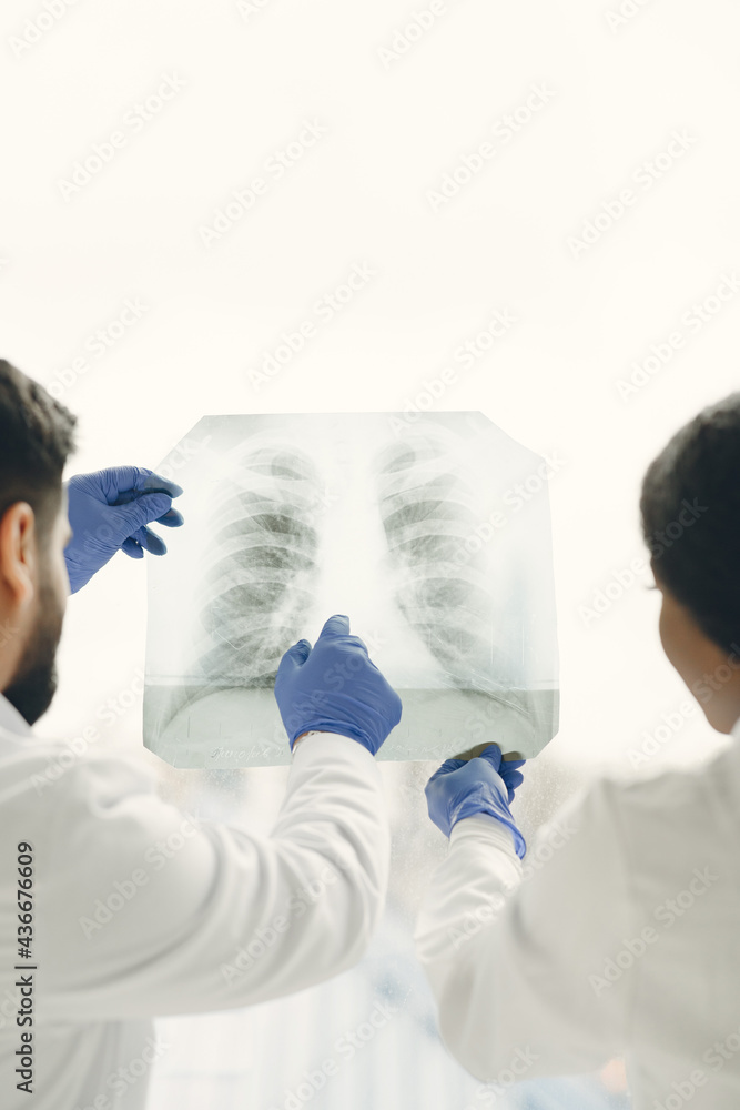 Doctor and coworker standing and looking at x-rays in clinic Doctor and coworker standing and looking at x-rays in clinic