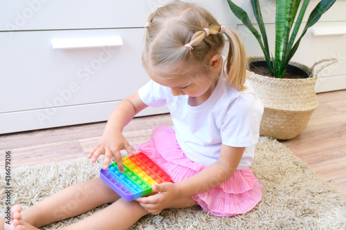 Cute faceless child playing with the Pop It fidget. Push pop bubble flexible fidget sensory toy