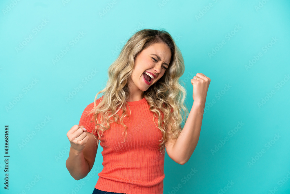 Fototapeta premium Young Brazilian woman isolated on blue background celebrating a victory