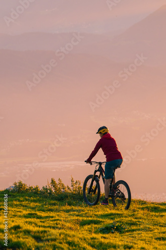 Woman riding mountain bike into the sunset. Beautiful golden summer light.