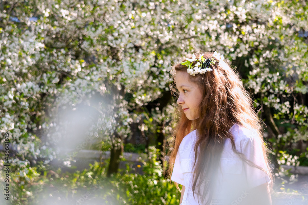 beautiful teenage girl with long blonde hair in white clothes enjoys the spring cherry blossom. A flower in her hair. Copy space beautiful teenage girl with long blonde hair in white clothes enjoys the spring cherry blossom. A flower in her hair. Copy space