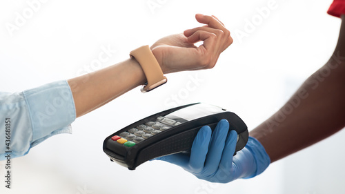 Black man holding POS machine woman paying with smart watch photo