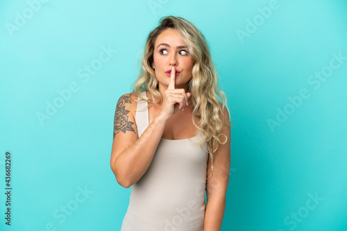 Young Brazilian woman isolated on blue background showing a sign of silence gesture putting finger in mouth