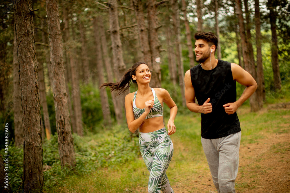 Fototapeta premium Young fitness couple running at the forest trail