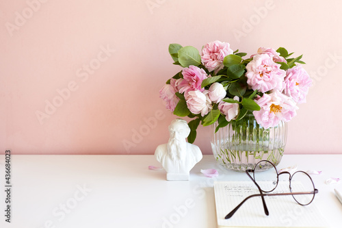 Wallpaper Mural Style, decoration, coziness, summer and design concept. Horizontal shot of beautiful peony flowers blossoming in glass vase, round eyesglasses on open book against blank pinkish background Torontodigital.ca