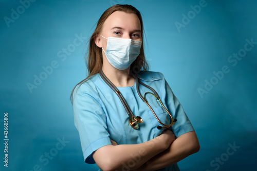 A doctor in a mask with a stethophonendoscope on a blue background photo