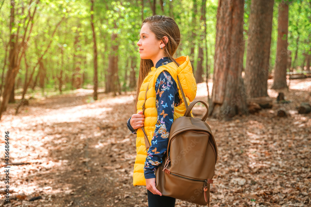 A little girl with a backpack walks through the spring forest, relaxation time, the concept of mental health A little girl with a backpack walks through the spring forest, relaxation time, the concept of mental health