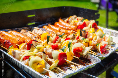 Grilled chicken and vegetable skewers and sausages on the grill
