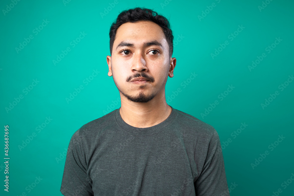 Portrait of thinking and confused young man on green background Portrait of thinking and confused young man on green background