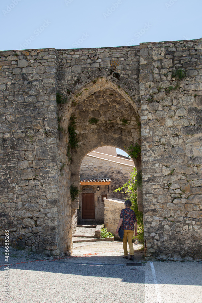 Femme touriste passant sous la porte d'entrée fortifiée du village de Cobonne dans la Drôme