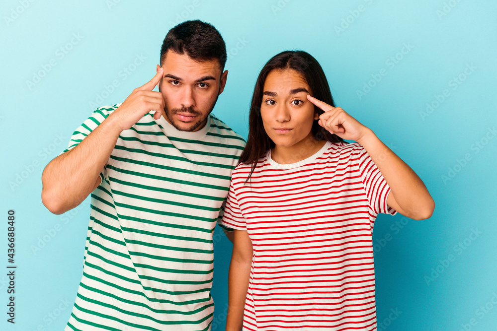 Young mixed race couple isolated on blue background pointing temple with finger, thinking, focused on a task. Young mixed race couple isolated on blue background pointing temple with finger, thinking, focused on a task.