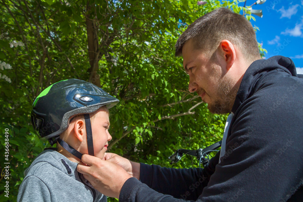 Father dad putting protection helmet for cycle on his son. Help and caring for children. City safety on scooter or bicycle. Father dad putting protection helmet for cycle on his son. Help and caring for children. City safety on scooter or bicycle.