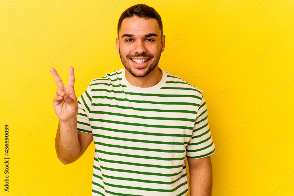 Fototapeta premium Young caucasian man isolated on yellow background showing victory sign and smiling broadly.