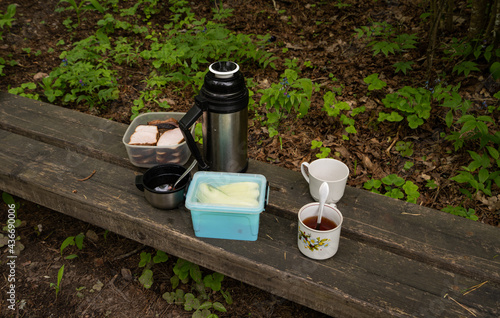 Picnic, teacup, meatbread, thermos on a wooden bench