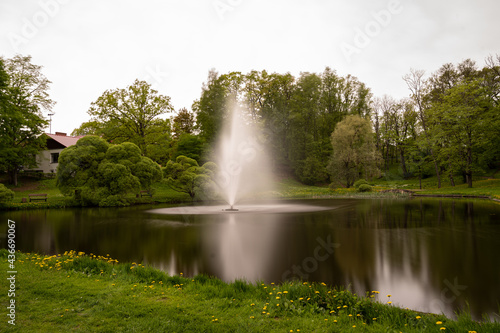 Fountain in a pond in the city, surrounded by trees and grass