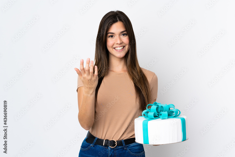 Teenager pastry chef holding a big cake over isolated white background inviting to come with hand. Happy that you came Teenager pastry chef holding a big cake over isolated white background inviting to come with hand. Happy that you came