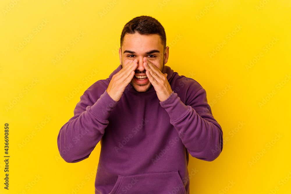 Young caucasian man isolated on yellow background saying a gossip, pointing to side reporting something. Young caucasian man isolated on yellow background saying a gossip, pointing to side reporting something.