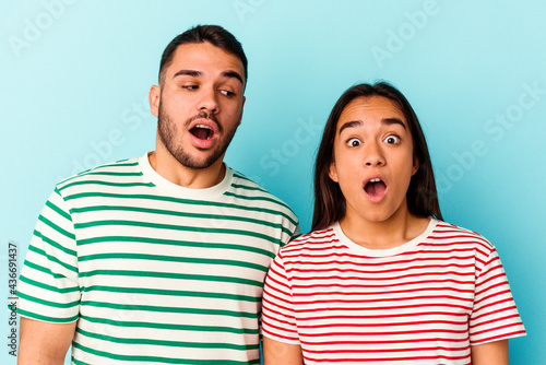 Young mixed race couple isolated on blue background © Asier