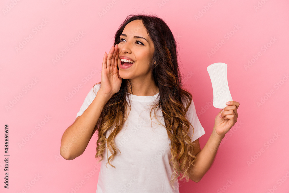 Young mexican woman holding a compress isolated on pink background shouting and holding palm near opened mouth. Young mexican woman holding a compress isolated on pink background shouting and holding palm near opened mouth.