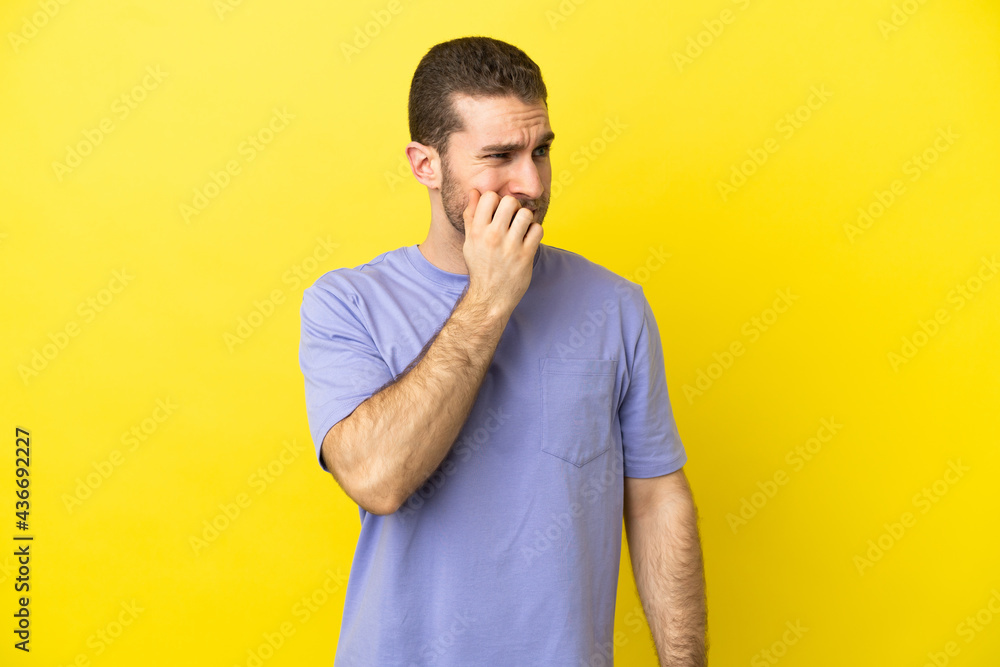 Handsome blonde man over isolated yellow background is a little bit nervous Handsome blonde man over isolated yellow background is a little bit nervous