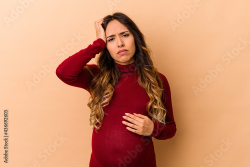 Young mexican pregnant woman isolated on beige background tired and very sleepy keeping hand on head.