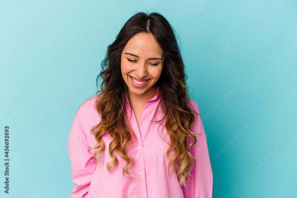 Young mexican woman isolated on blue background laughs and closes eyes, feels relaxed and happy. Young mexican woman isolated on blue background laughs and closes eyes, feels relaxed and happy.