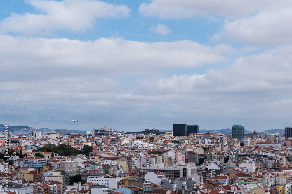 Passenger plane approaching landing over Lisbon city centre rooftops