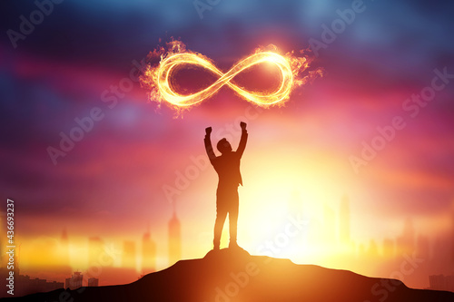 Infinity Fire Sign over the silhouette of a businessman on a sunset background