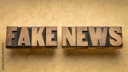 fake news word abstract in vintage letterpress wood type against grunge paper, social media and infodemic concept photo