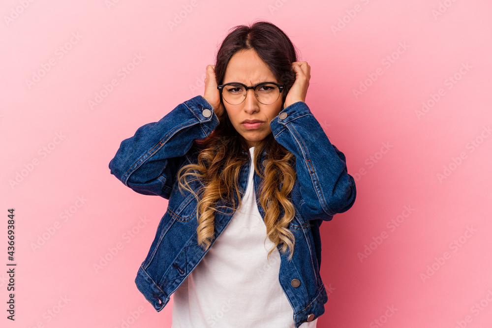 Young mexican woman isolated on pink background covering ears with hands trying not to hear too loud sound. Young mexican woman isolated on pink background covering ears with hands trying not to hear too loud sound.