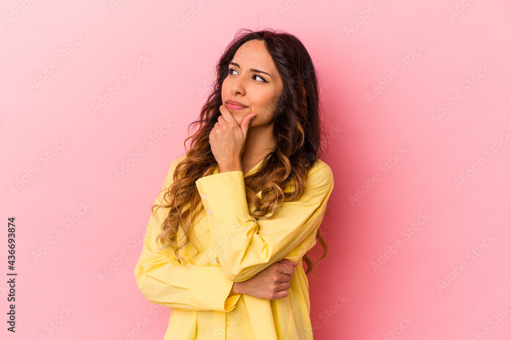 Young mexican woman isolated on pink background thinking and looking up, being reflective, contemplating, having a fantasy. Young mexican woman isolated on pink background thinking and looking up, being reflective, contemplating, having a fantasy.
