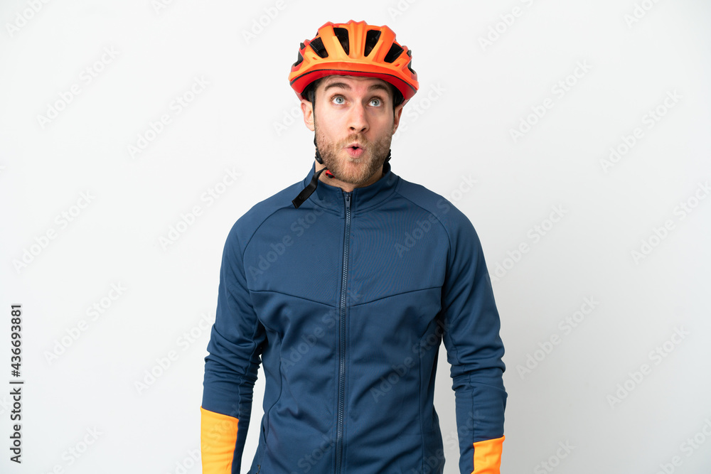 Young cyclist man isolated on white background looking up and with surprised expression Young cyclist man isolated on white background looking up and with surprised expression