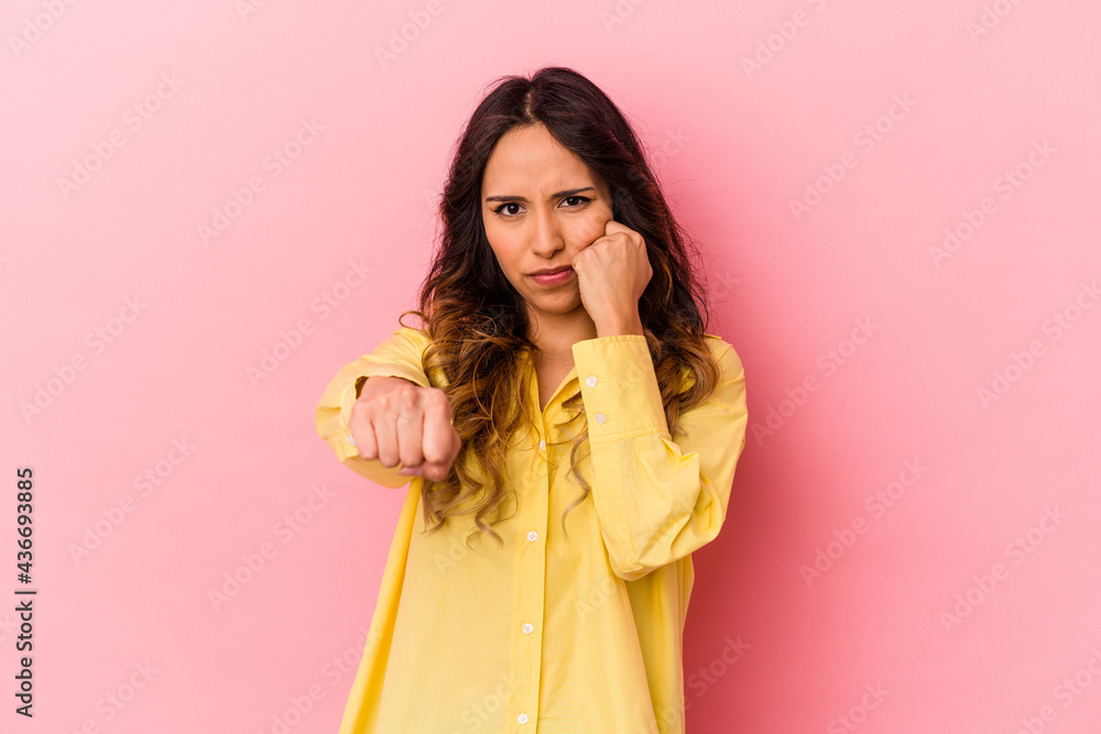 Young mexican woman isolated on pink background throwing a punch, anger, fighting due to an argument, boxing. Young mexican woman isolated on pink background throwing a punch, anger, fighting due to an argument, boxing.