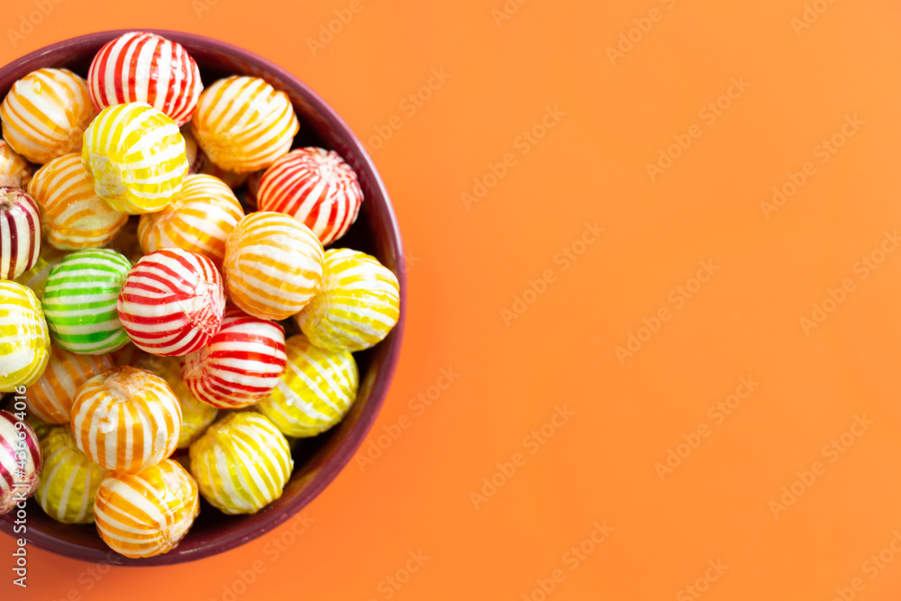 colorful candies in bowl on colored background