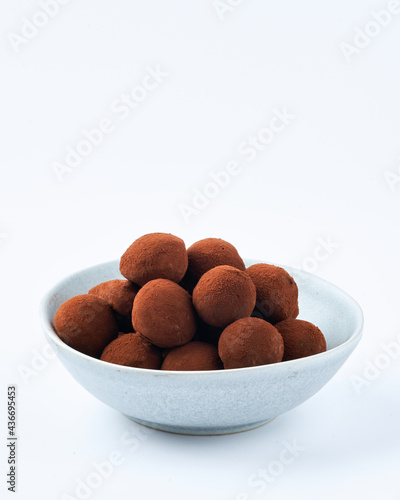 Chocolate truffles on a marble cutting board, white background, copy space. Selective focus, dessert concept. Close up.