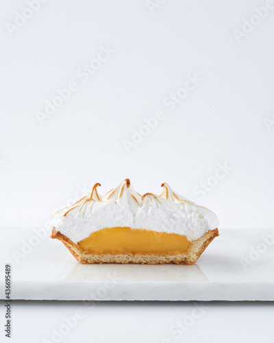 Lemon Curd and Meringue Mini Tart Pie interior on white background, selective focus, copy space. Bakery pastry dessert concept.