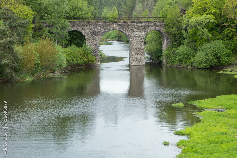Old antique stone arch bridge over a river in forest landscape. Spring country in EU Old antique stone arch bridge over a river in forest landscape. Spring country in EU